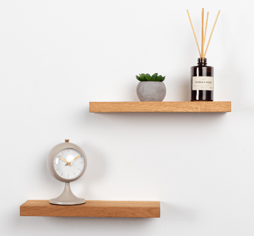 Wooden shelves with a clock, plant, and diffuser on a white wall