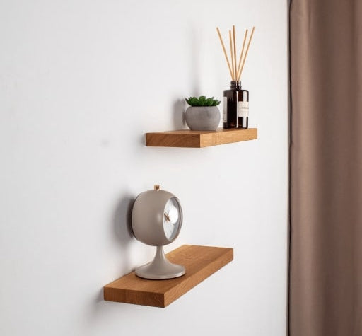 Two wooden shelves with decorative items against a white wall.
