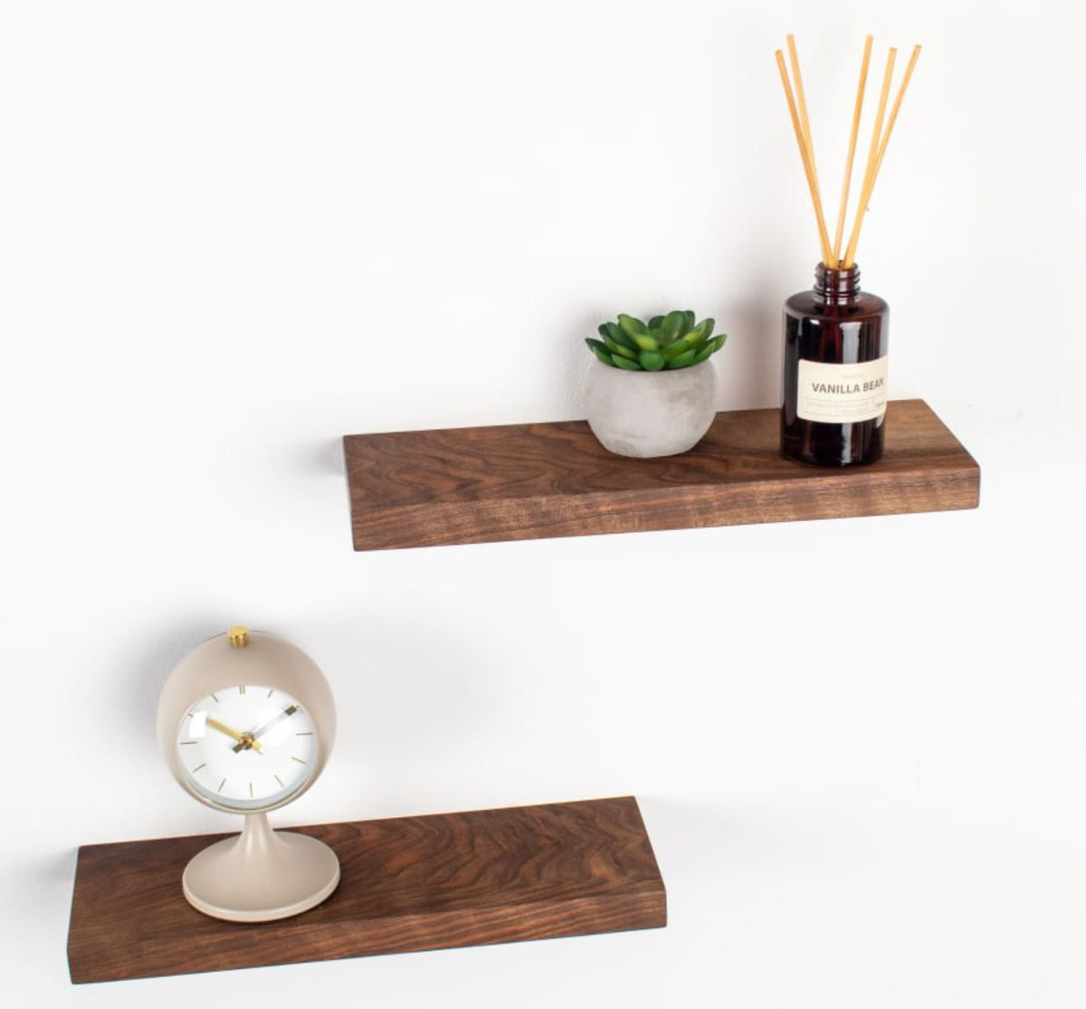 Wooden shelves with a clock, plant, and diffuser on a white background