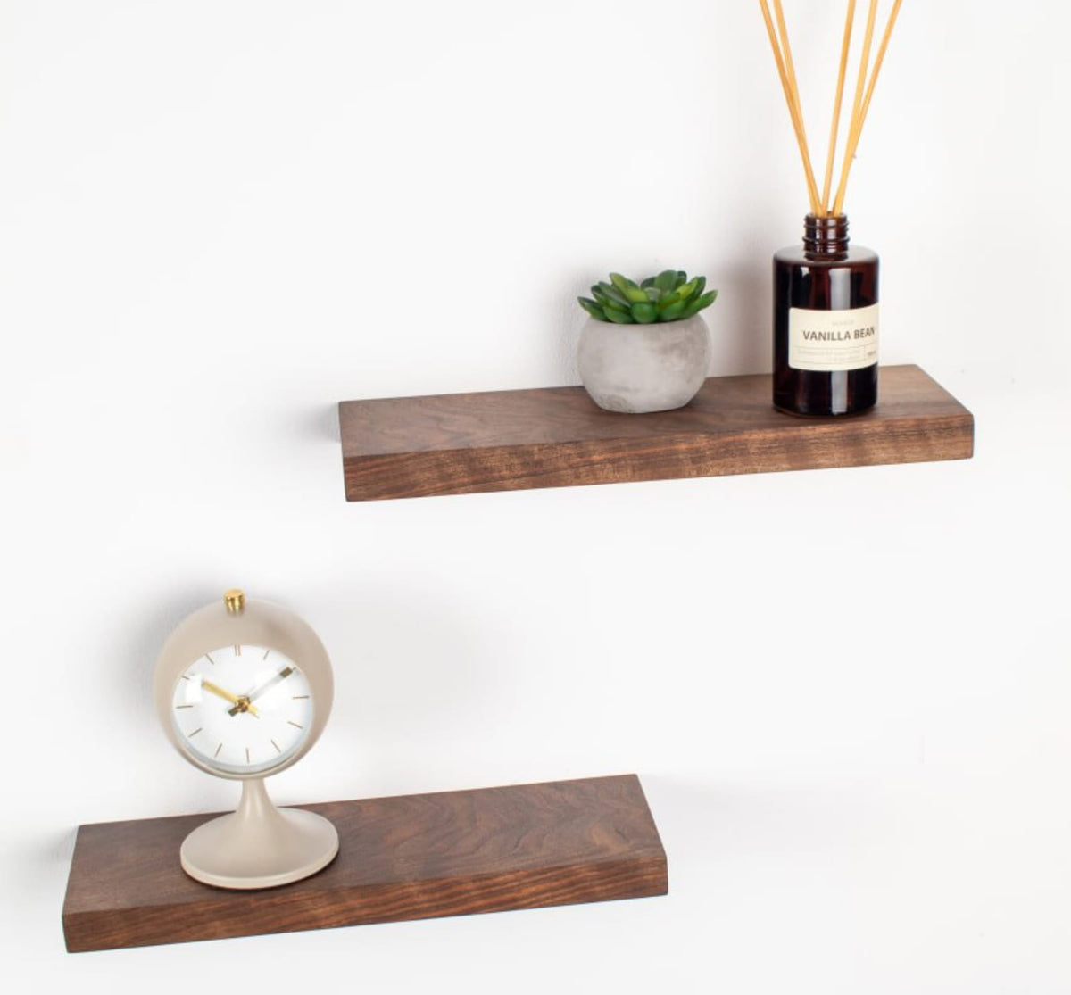 Wooden shelves with a clock, plant, and diffuser on a white background