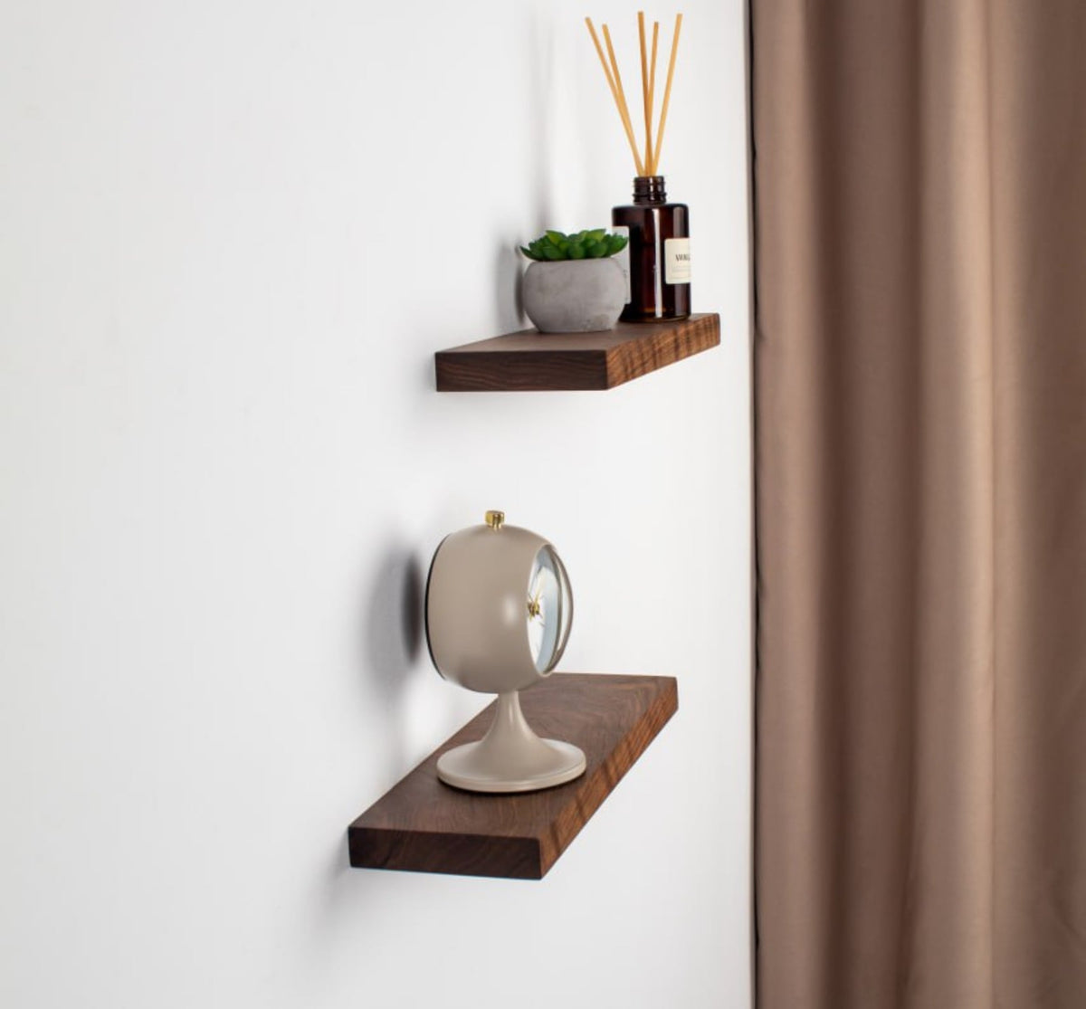 Two wooden shelves with decorative items against a white wall.