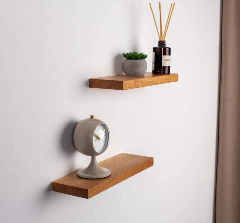 Two wooden shelves with decorative items on a light gray wall.