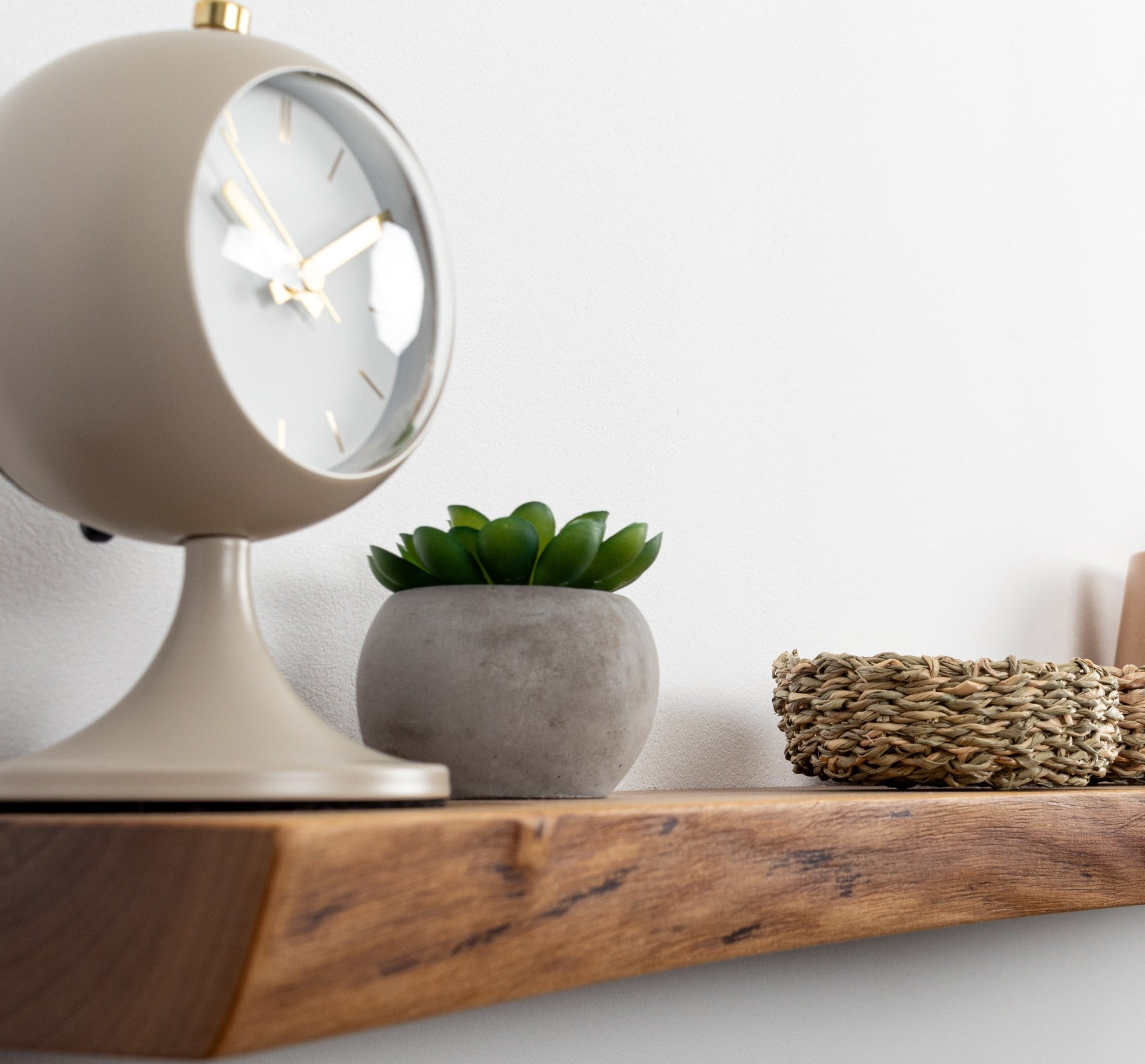 Decorative shelf with a clock, plant, and woven basket on a white background