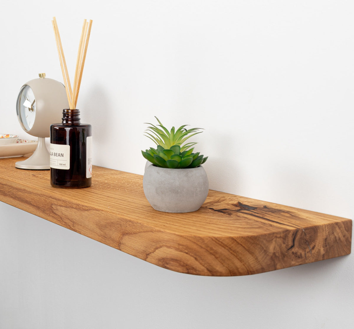 Wooden shelf with a plant, diffuser, and decorative items on a white background