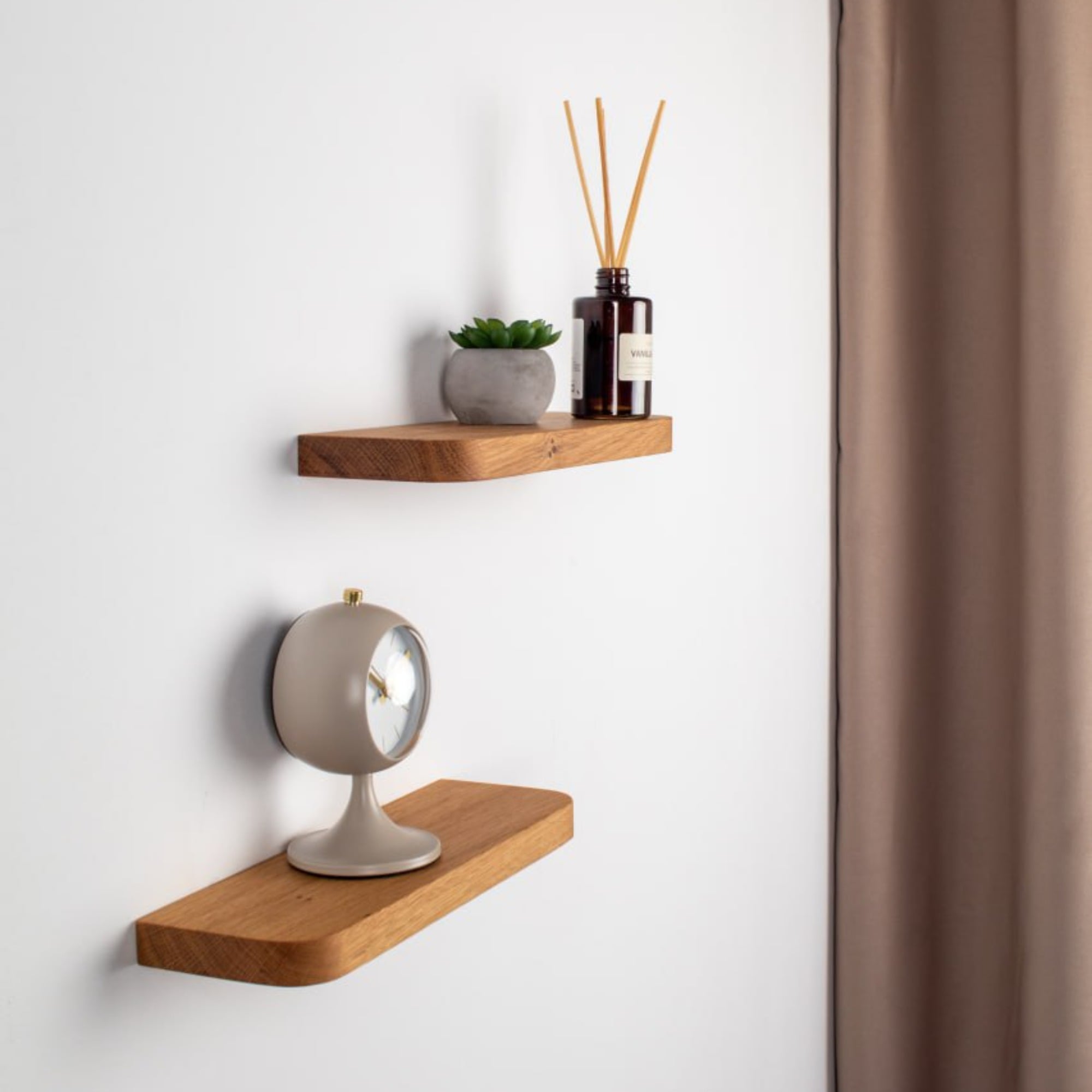 Two wooden shelves with decorative items on a white wall.