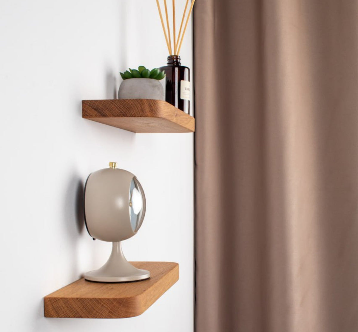Wooden shelves with decorative items against a white wall with a brown curtain.