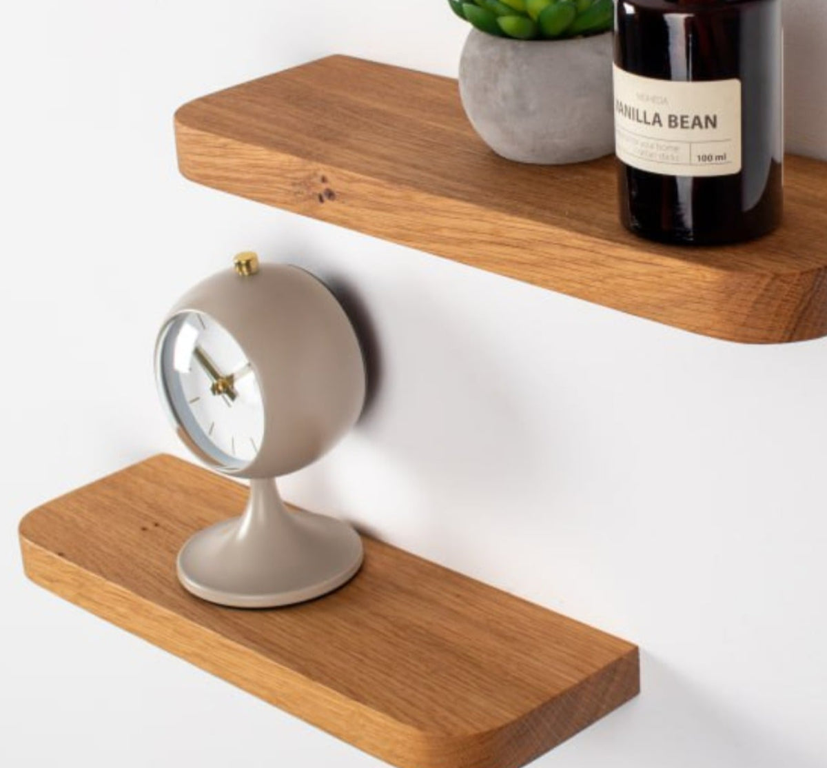 Wooden shelves with a vanilla bean diffuser, plant, and clock on a white background