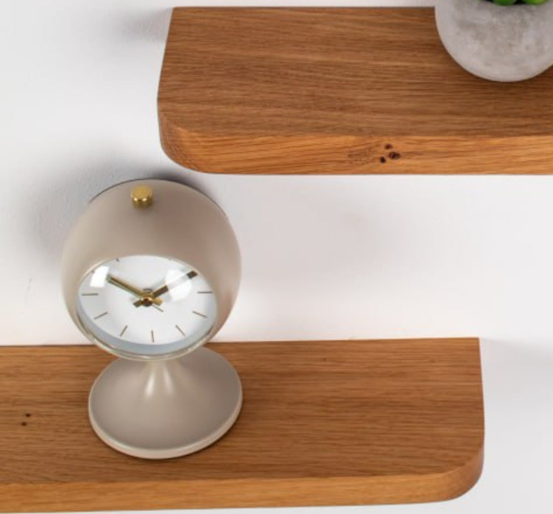 Wooden shelves with a clock, plant, and diffuser on a white background