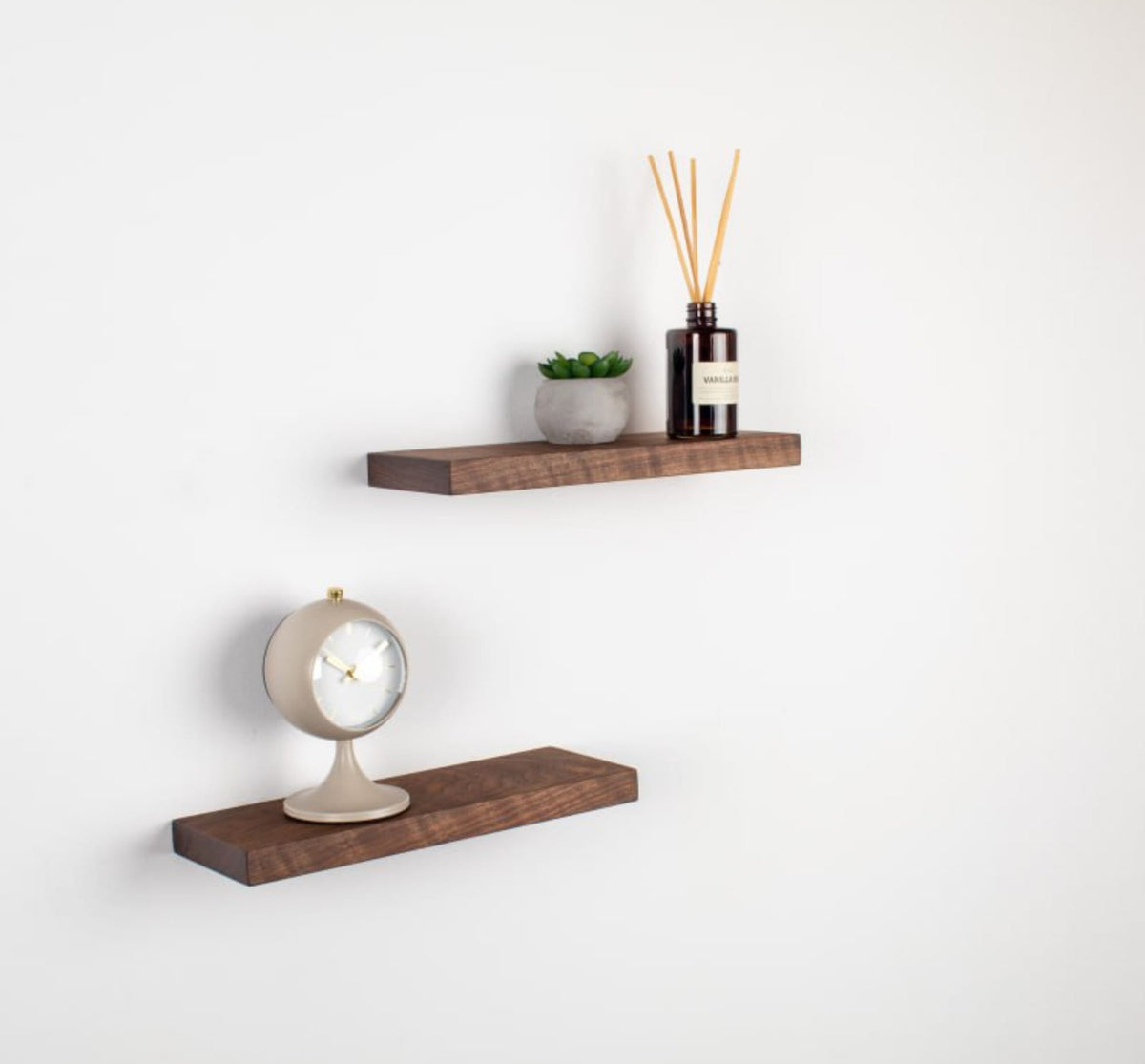 Two wooden shelves with decorative items on a white wall