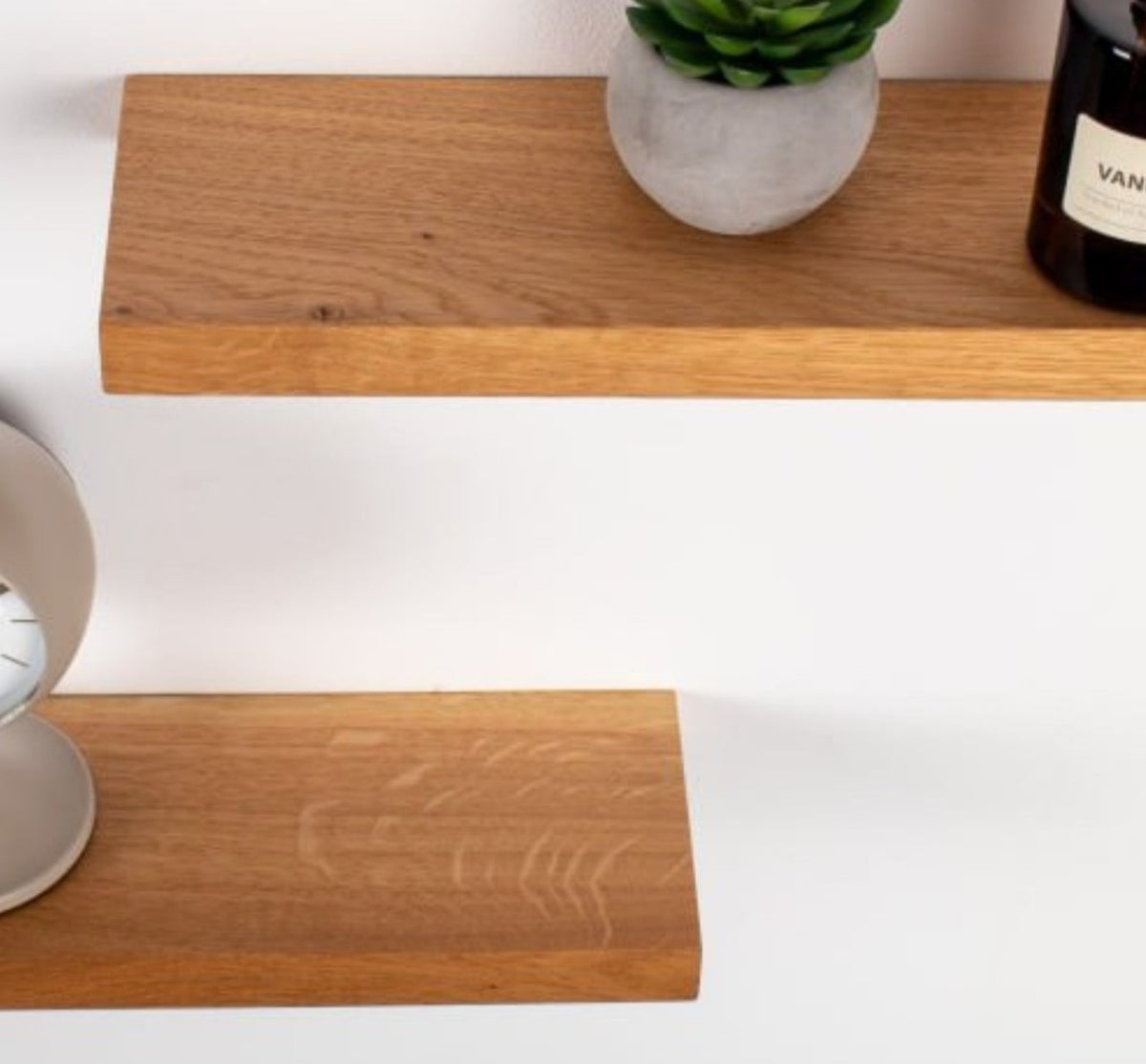 Wooden shelf with a plant and candle on a white background