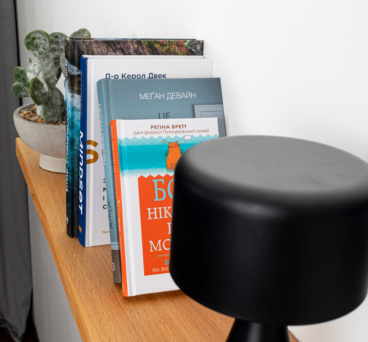 Black stool on a wooden floor with books and a plant in the background