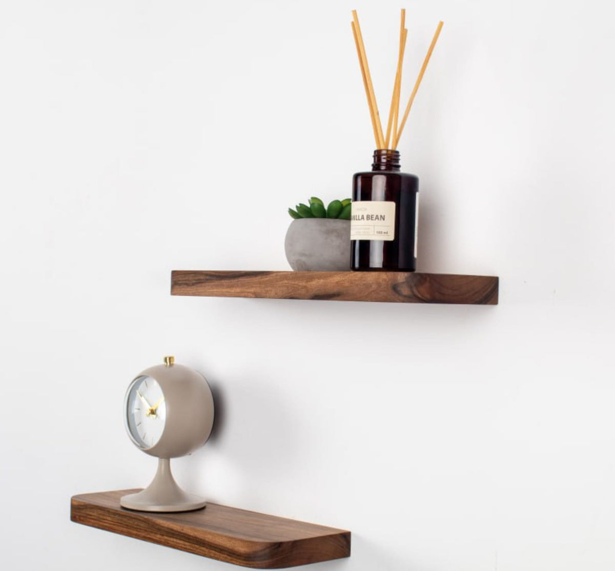 Two wooden shelves with decorative items on a white wall