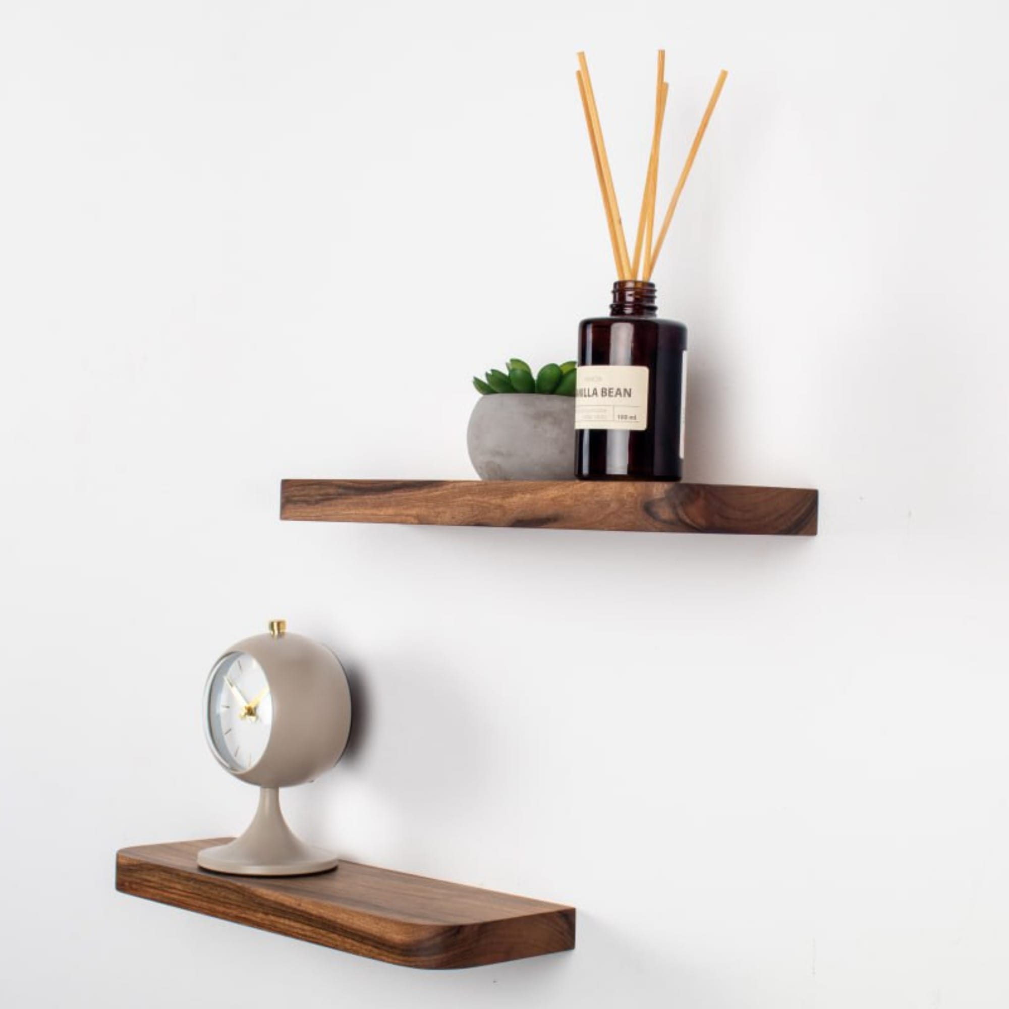Two wooden shelves with decorative items on a white wall