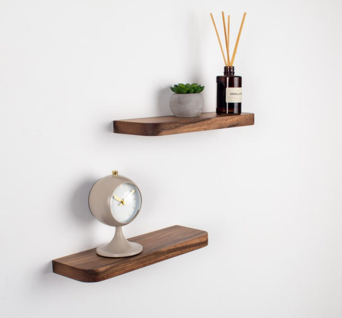 Two wooden shelves with decorative items on a white wall.