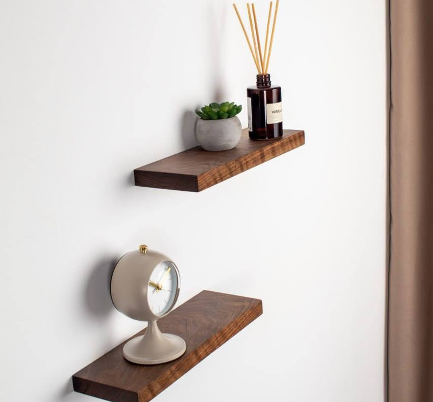 Two wooden shelves on a white wall with decorative items.