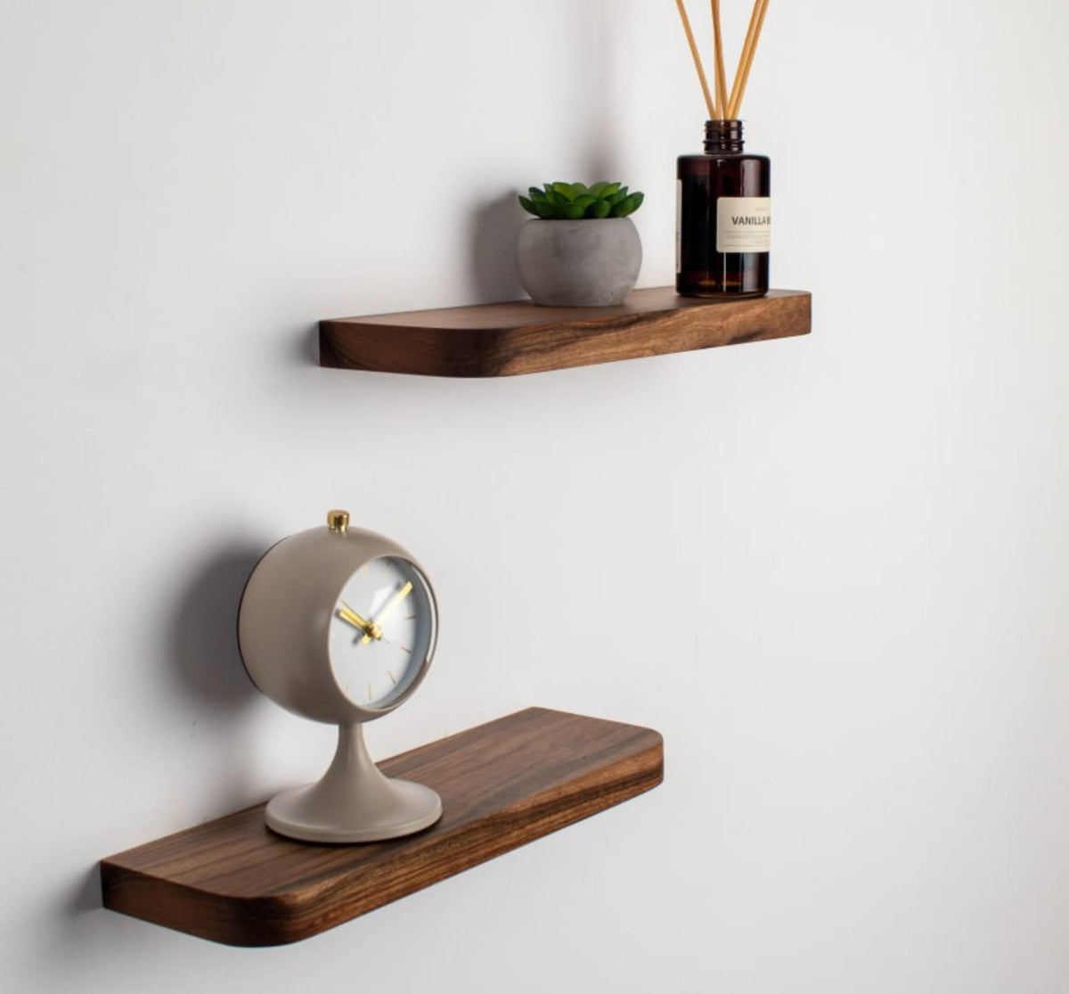 Wooden shelves with a clock and decorative items on a white wall