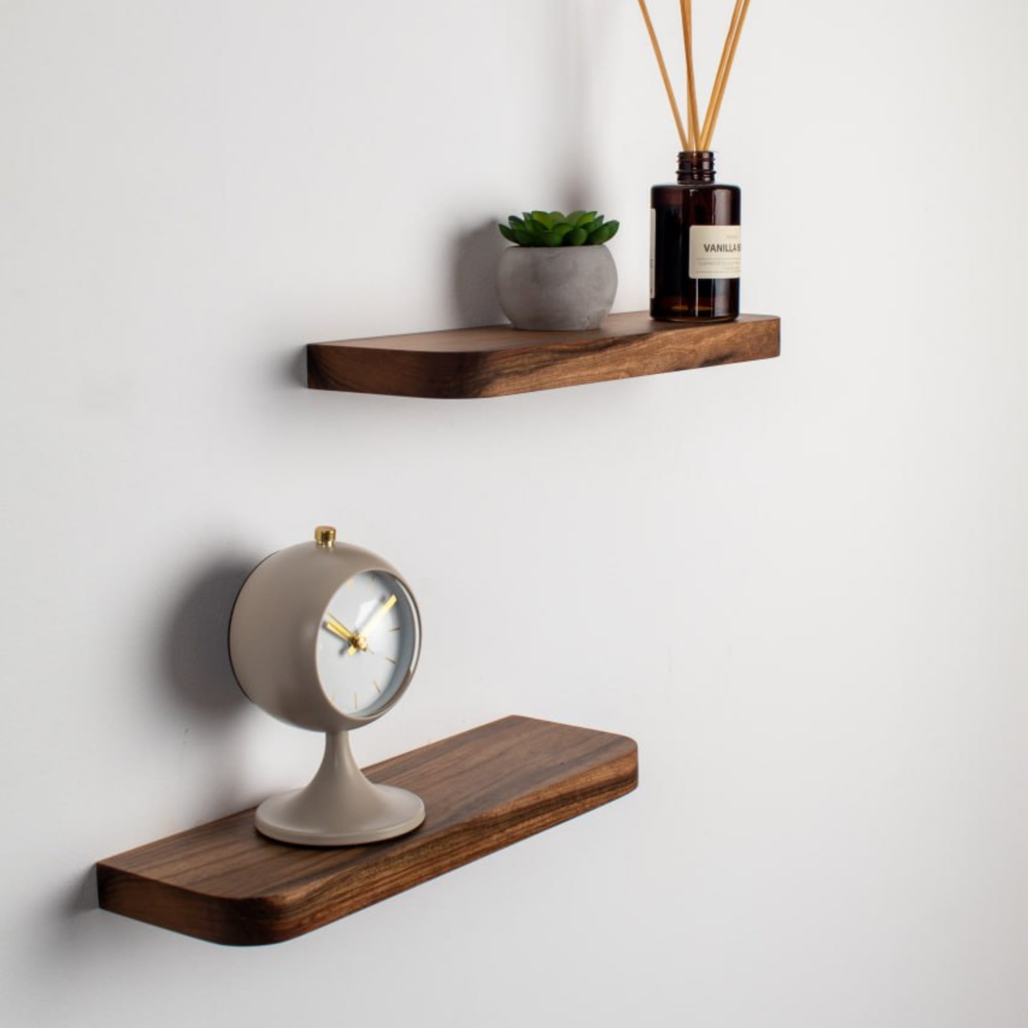 Wooden shelves with a clock and decorative items on a white wall