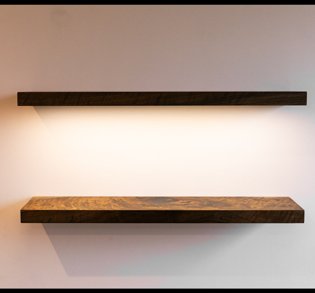 Two wooden shelves on a plain wall