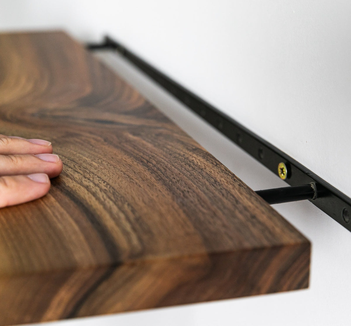 Wooden surface with a hand touching it, mounted on a white wall.