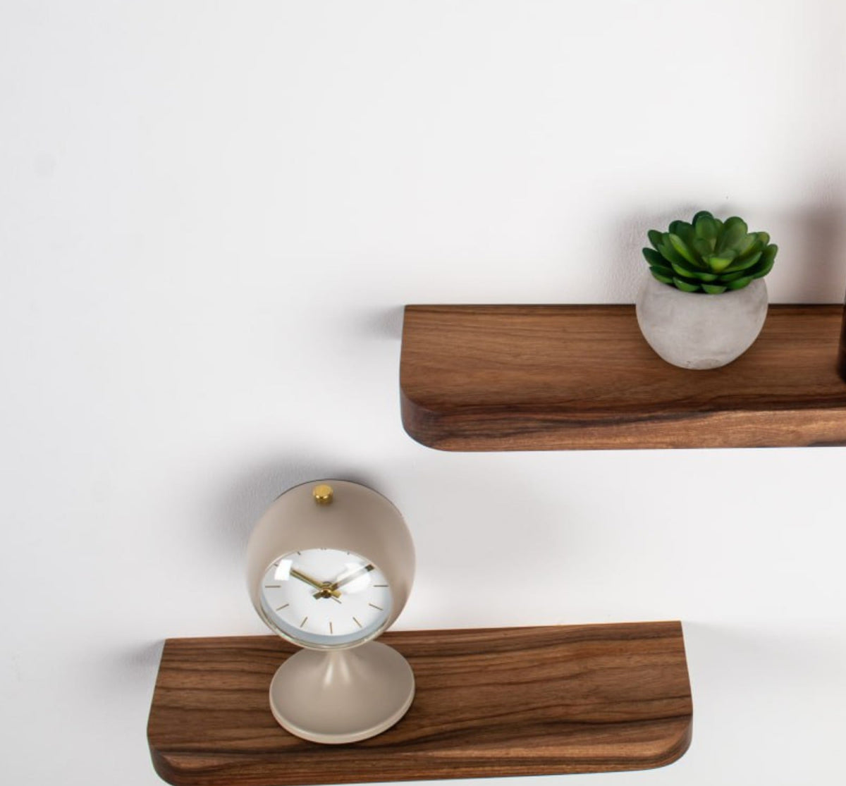 Wooden shelves with a clock and small plant on a white background
