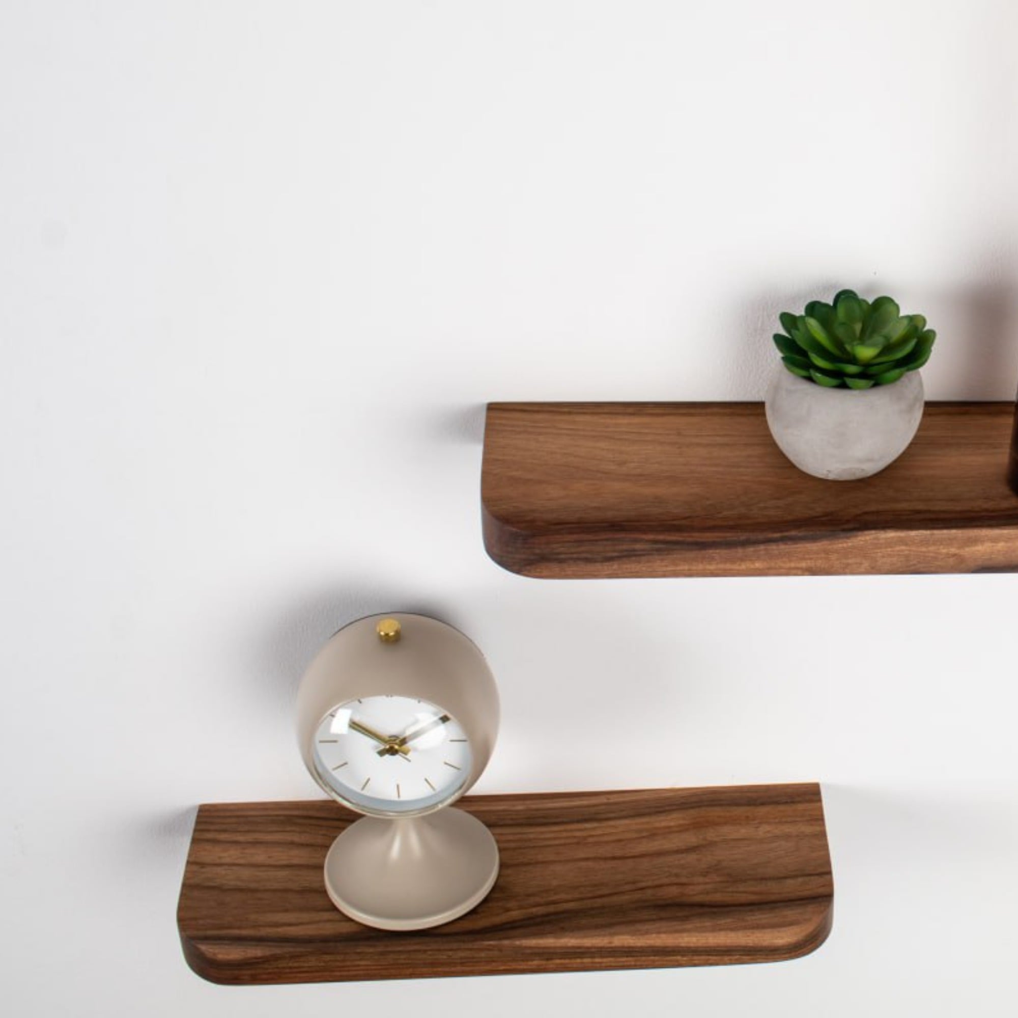 Wooden shelves with a clock and small plant on a white background