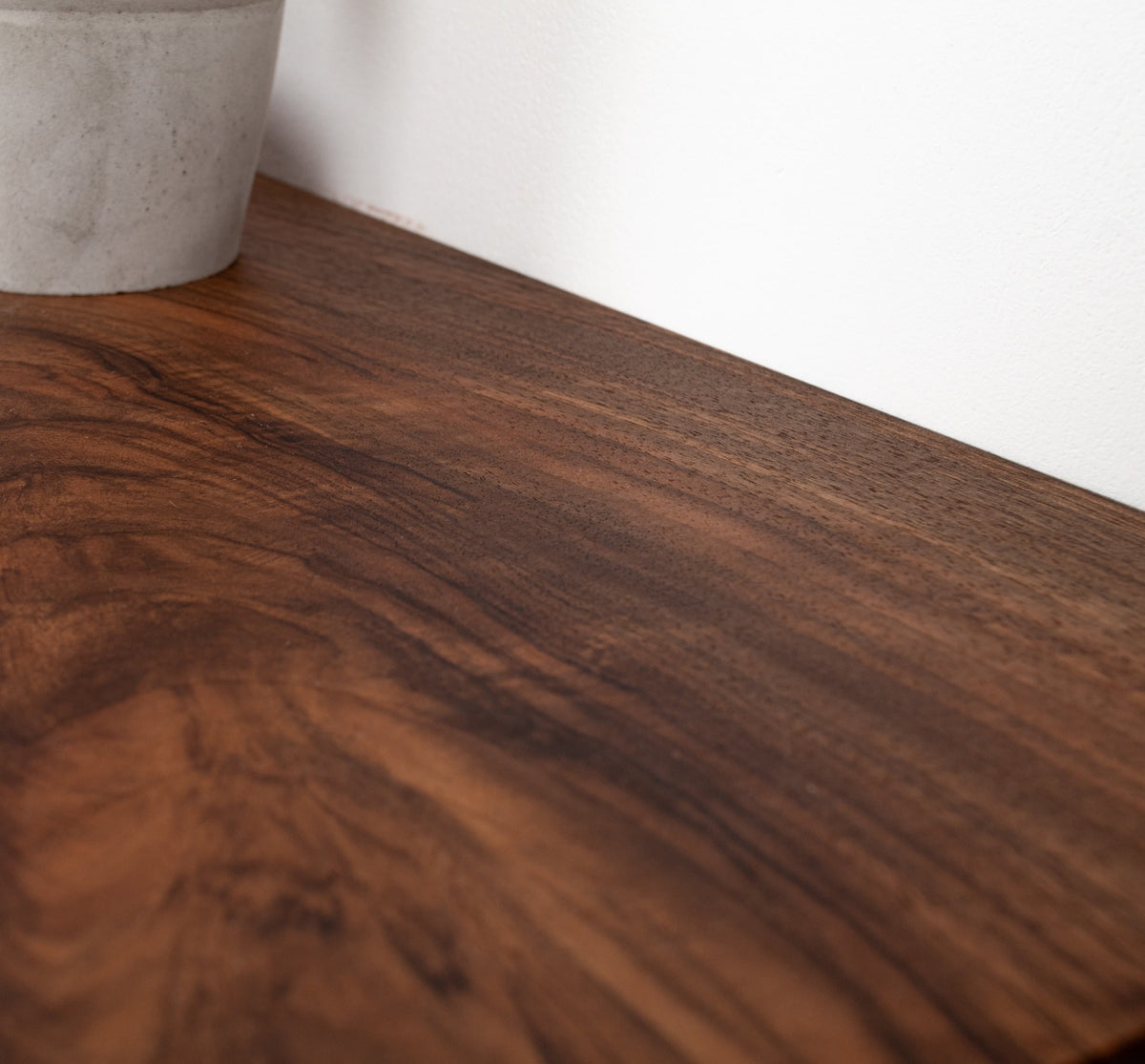 Close-up of a wooden surface with a white wall in the background