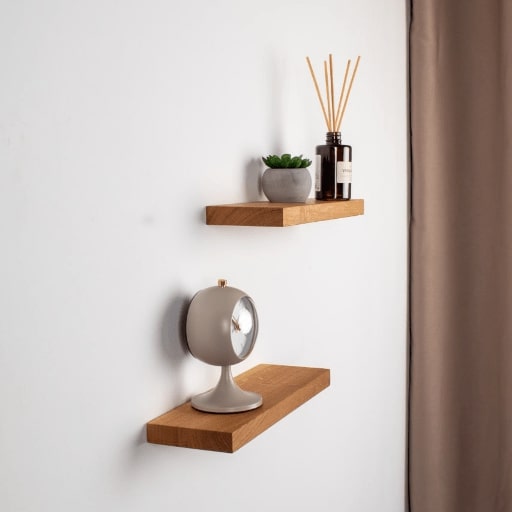 Two wooden shelves with decorative items against a white wall.