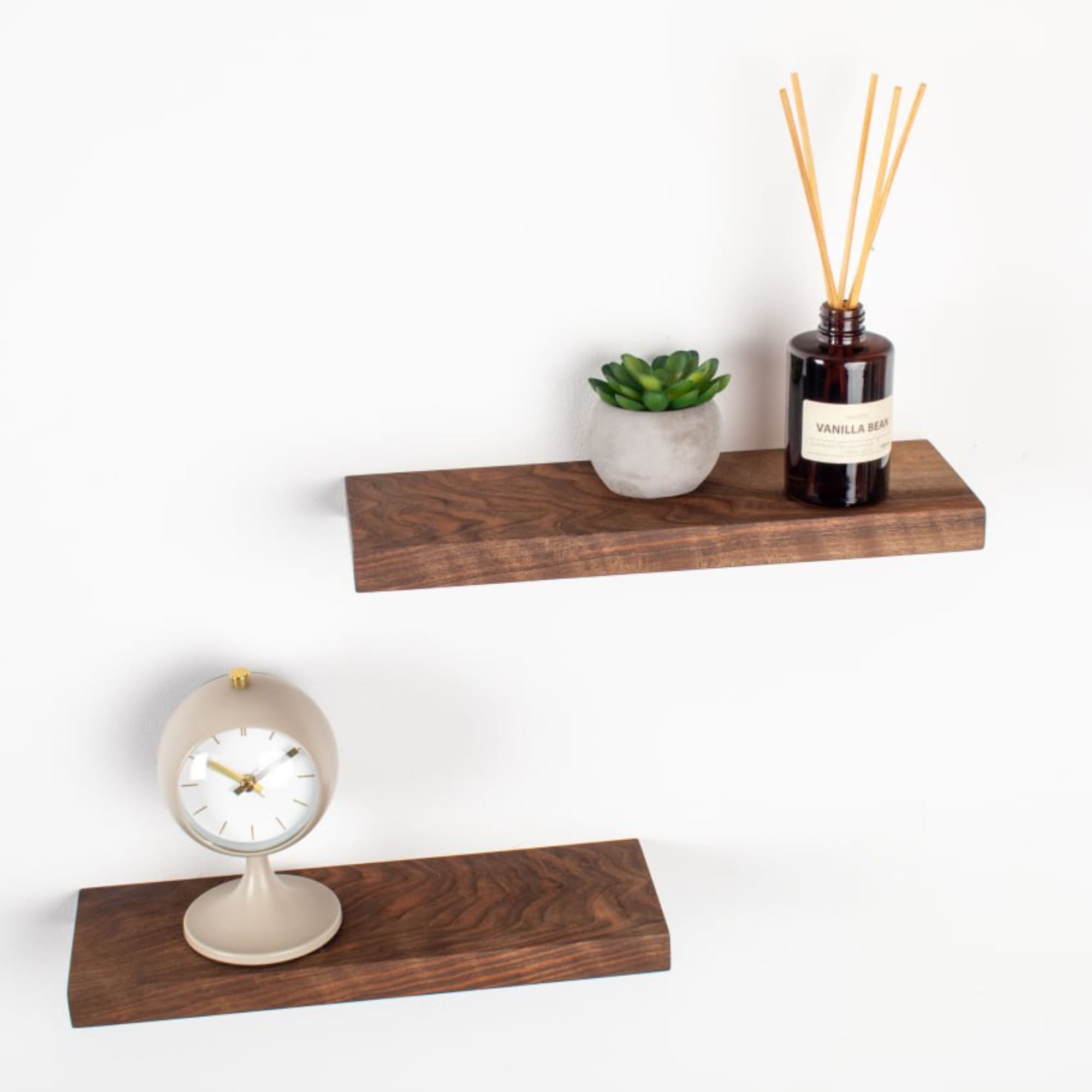 Wooden shelves with a clock, plant, and diffuser on a white background