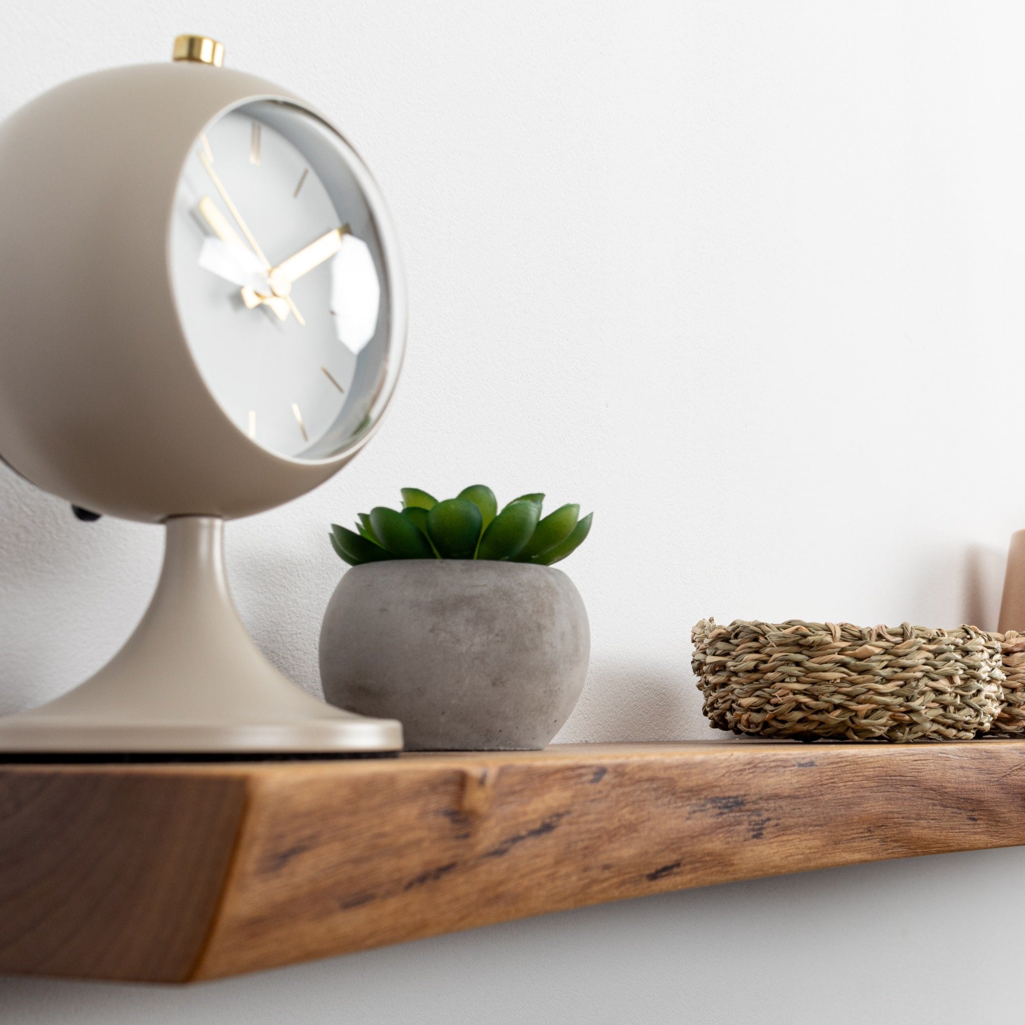 Decorative shelf with a clock, plant, and woven basket on a white background