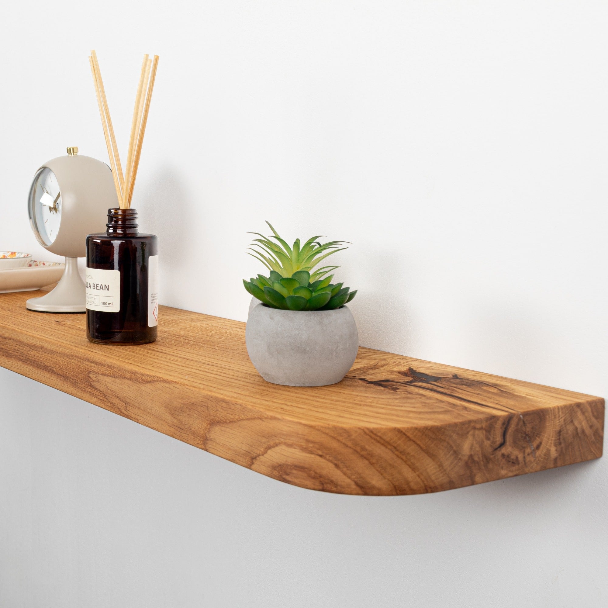 Wooden shelf with a plant, diffuser, and decorative items on a white background