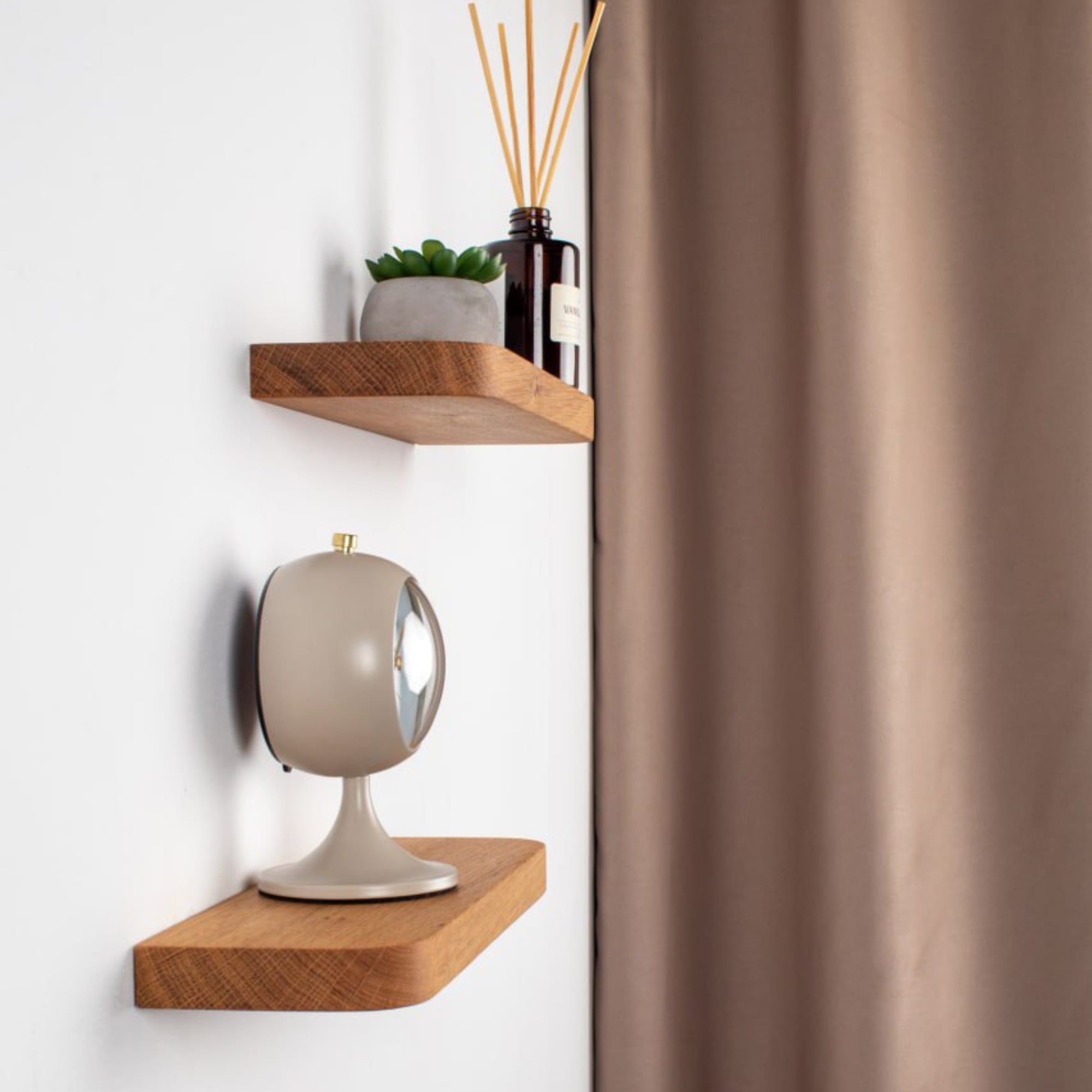 Wooden shelves with decorative items against a white wall with a brown curtain.