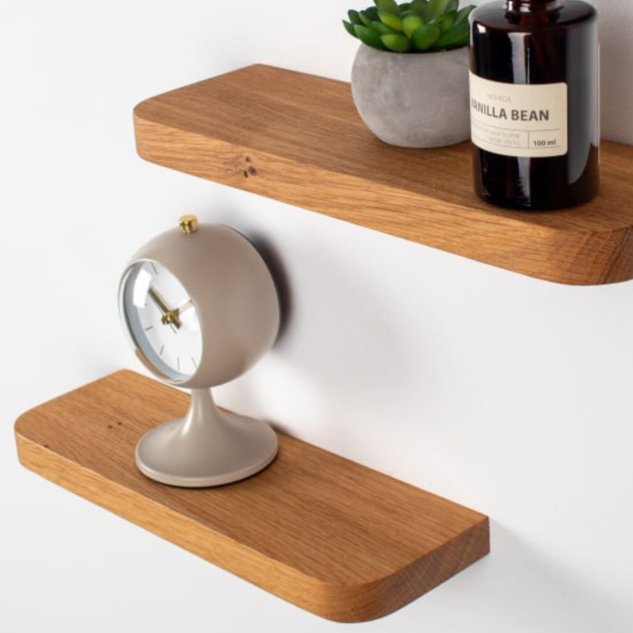 Wooden shelves with a vanilla bean diffuser, plant, and clock on a white background