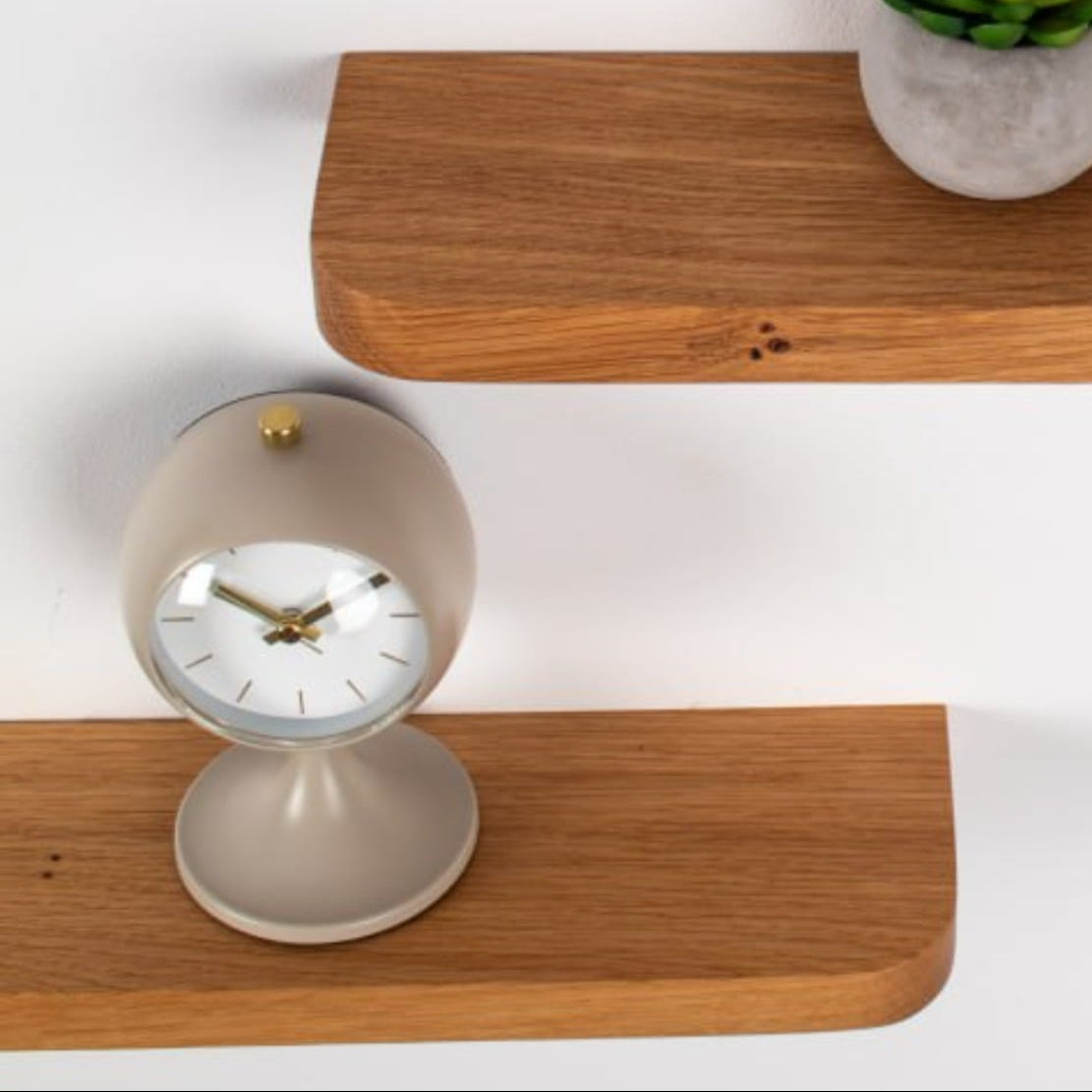 Wooden shelves with a clock, plant, and diffuser on a white background