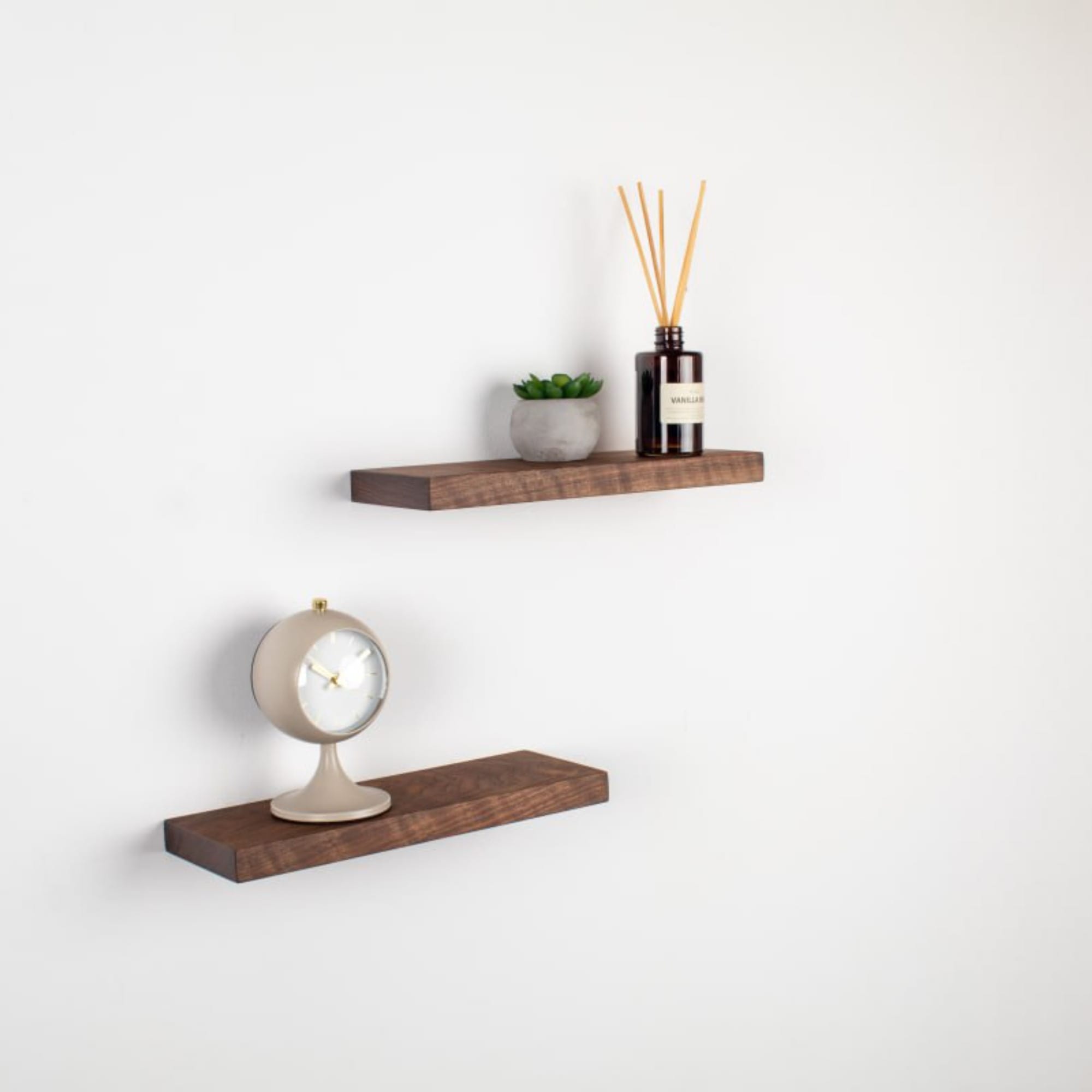 Two wooden shelves with decorative items on a white wall