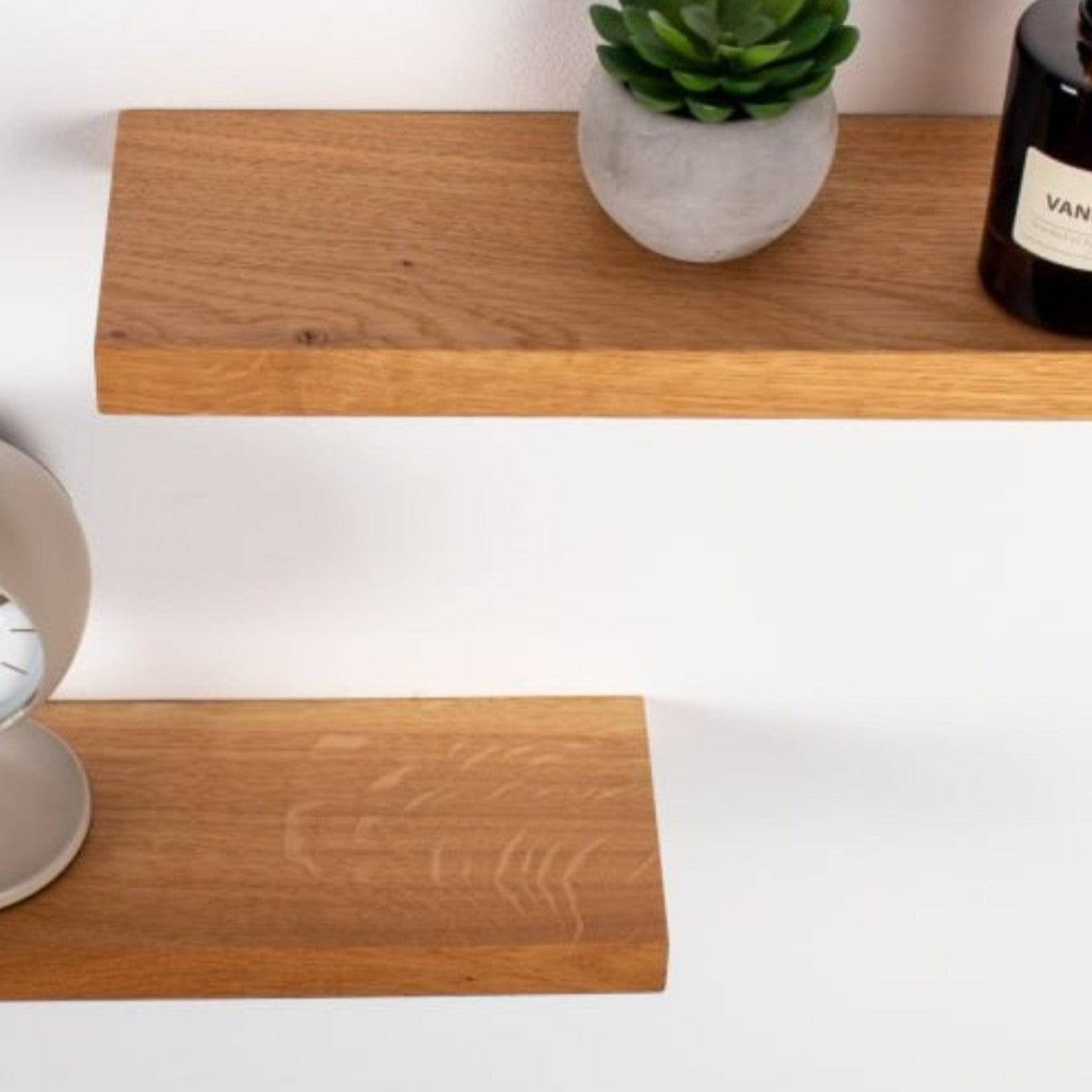 Wooden shelf with a plant and candle on a white background