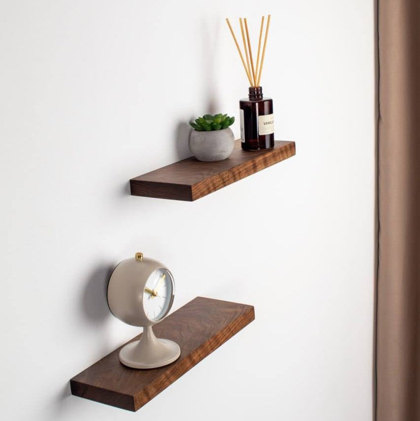 Two wooden shelves on a white wall with decorative items.