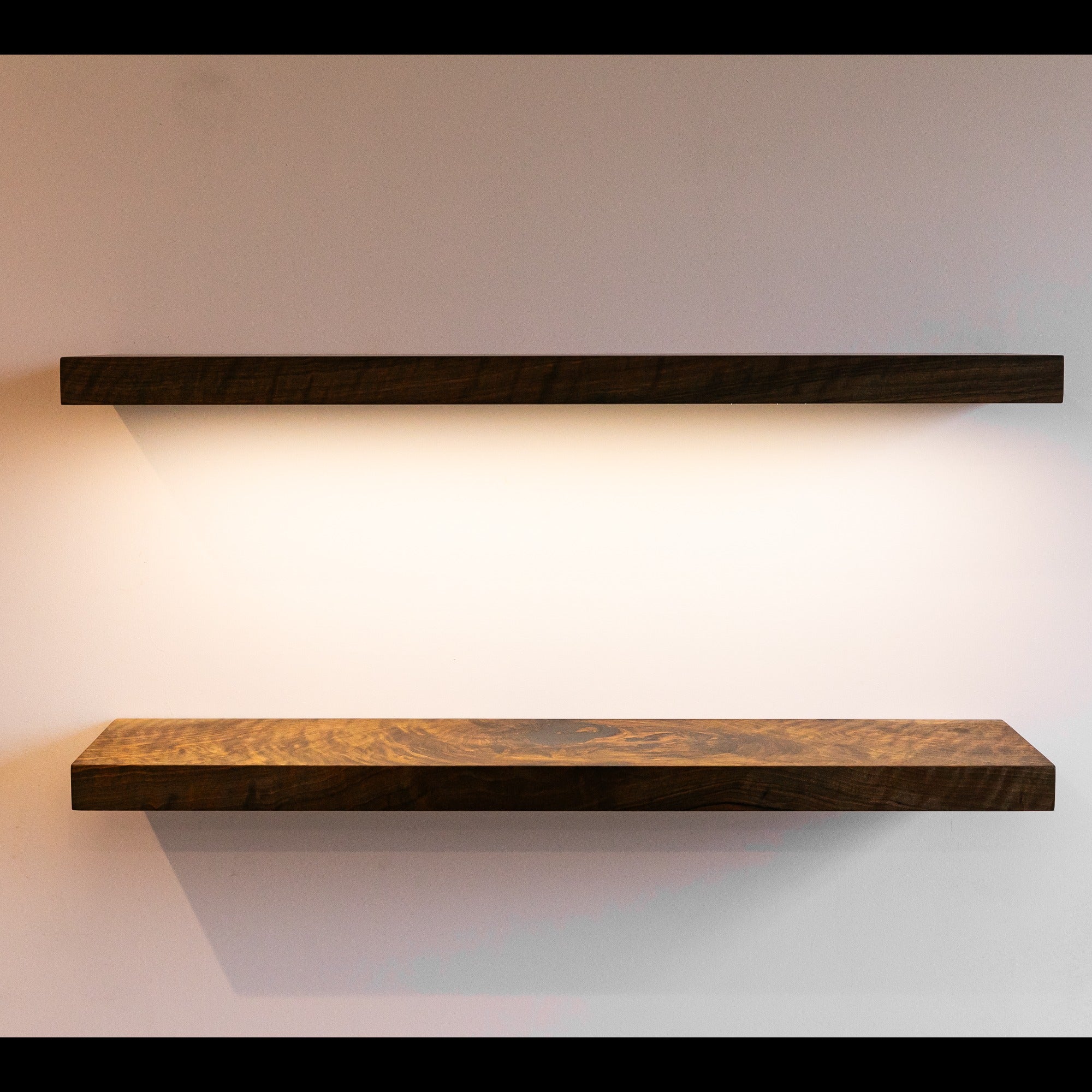 Two wooden shelves on a plain wall