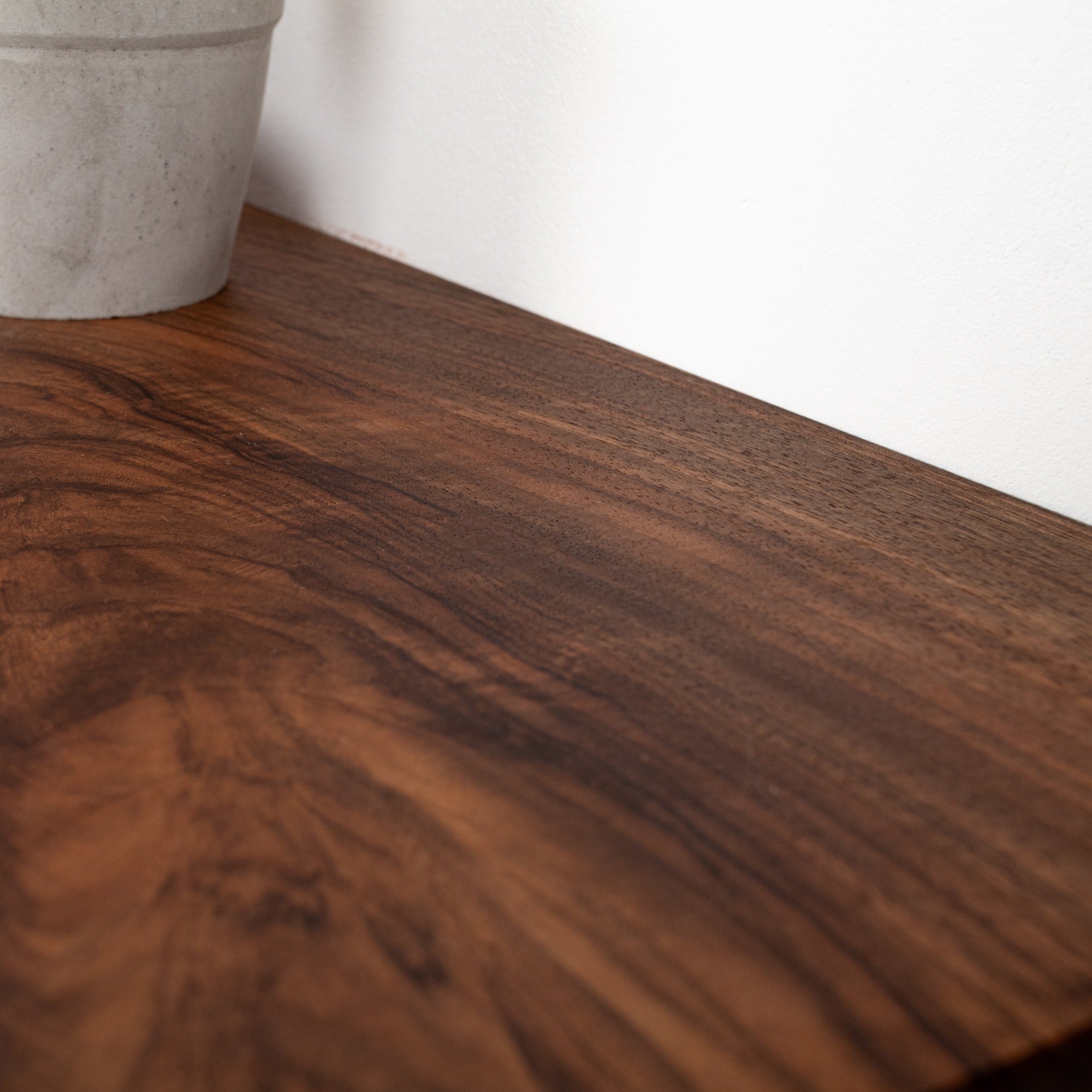 Close-up of a wooden surface with a white wall in the background